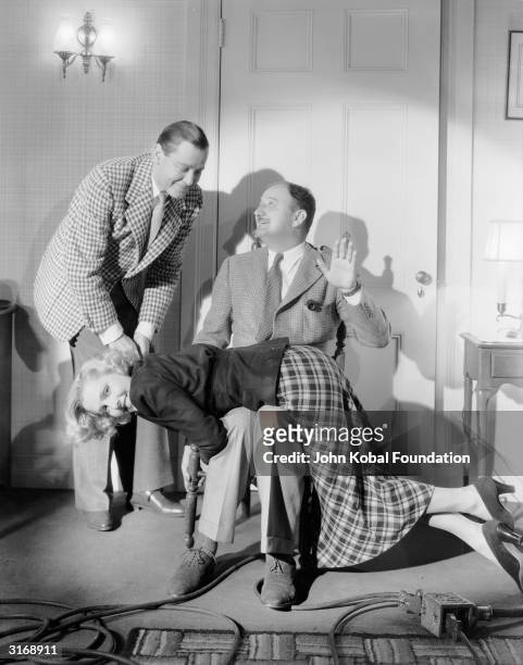 Rehearsing a scene, an amused Jean Arthur gets a spanking, watched by Herbert Marshall , during the filming of 'If You Could Only Cook' , directed by...