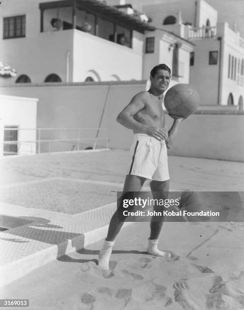 British born actor Cary Grant , born Archibald Leach, playing with a ball at the beach house he shared with the American actor, Randolph Scott.