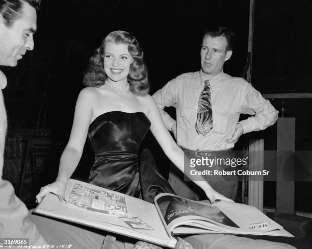 American film actress, dancer and singer Rita Hayworth looks through a scrap book as she takes a break during the filming of the 1946 film-noir...