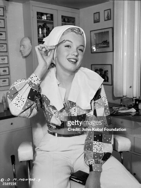 American film star Marilyn Monroe , born Norma Jean Mortensen in Los Angeles, begins the process of applying her make-up.