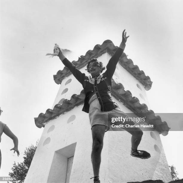 Spanish surrealist artist Salvador Dali cavorting with arms raised on a rooftop at his home in Cadaques on the Costa Brava, Spain. Original...