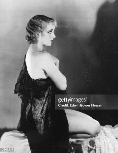 American film actress Carole Lombard lets her dress slip off one shoulder.