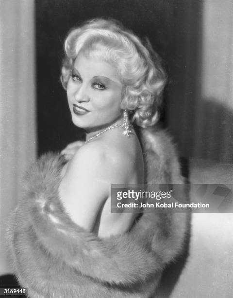 Mae West bares her shoulder from underneath a fur stole.
