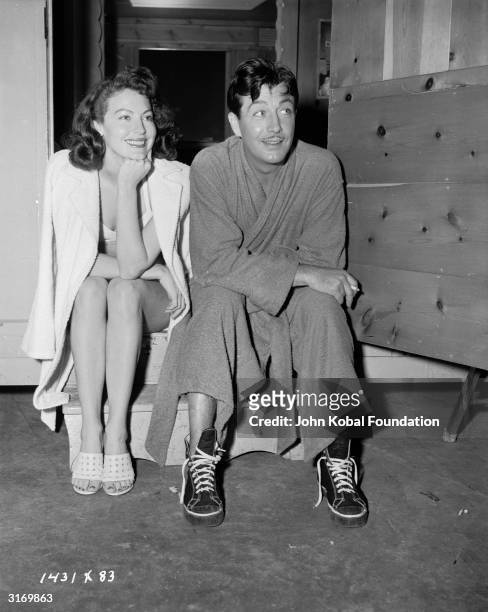 American film star Ava Gardner sitting with actor Robert Taylor on the set of the film noir 'The Bribe', directed by Robert Z Leonard.