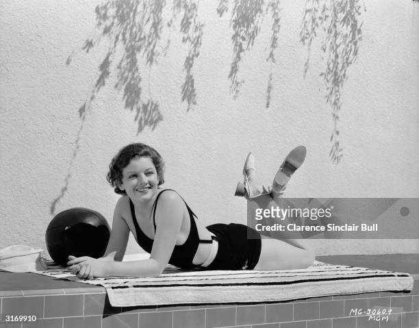 American actress Myrna Loy enjoying a spot of sunbathing.