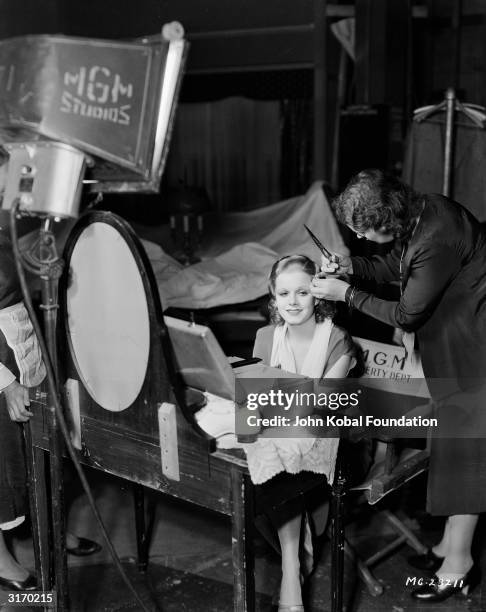 Platinum blonde star Jean Harlow is having her hair trimmed between takes of 'Red-Headed Woman', directed by Jack Conway.