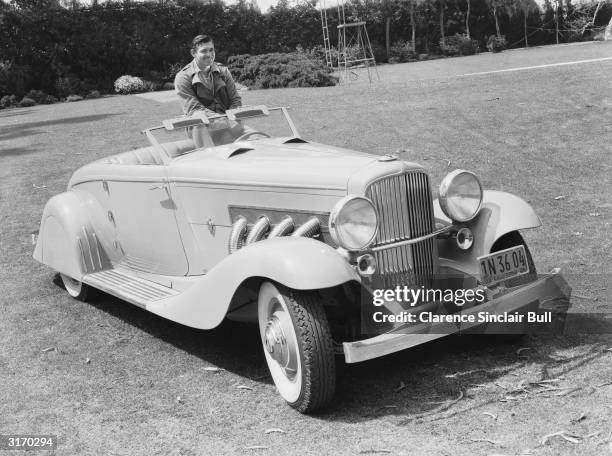 American screen star Clark Gable , known as the 'King of Hollywood', poses in his custom-bodied Duesenberg J roadster by Bohman and Scwartz, 2nd...