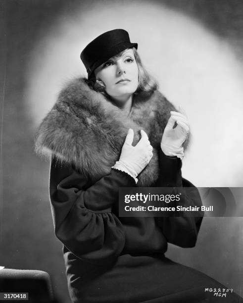 Star Greta Garbo wearing a coat with a fur collar and a small hat with a flat crown for her role as Grusinskaya in 'Grand Hotel', directed by Edmund...