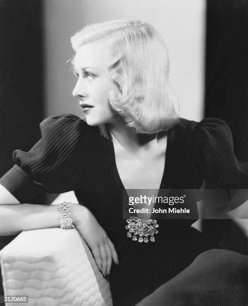 American dancer and actress Ginger Rogers wearing a low cut evening dress with a large jewelled brooch.