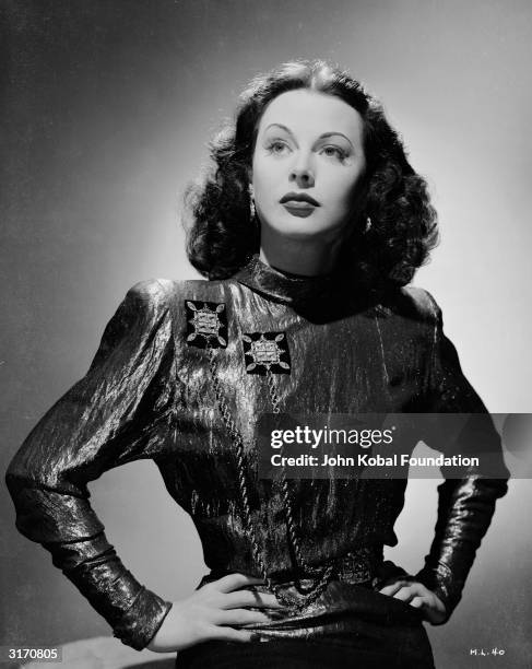 Austrian born actress Hedy Lamarr stands with her hands on her hips, wearing a shimmering blouse decorated with cord. She is starring as Irene in...