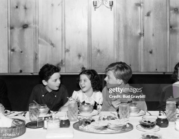 British child actor Freddie Bartholomew and his American colleague Mickey Rooney, enjoy some ice cream and a joke with the child star Peggy Ryan.