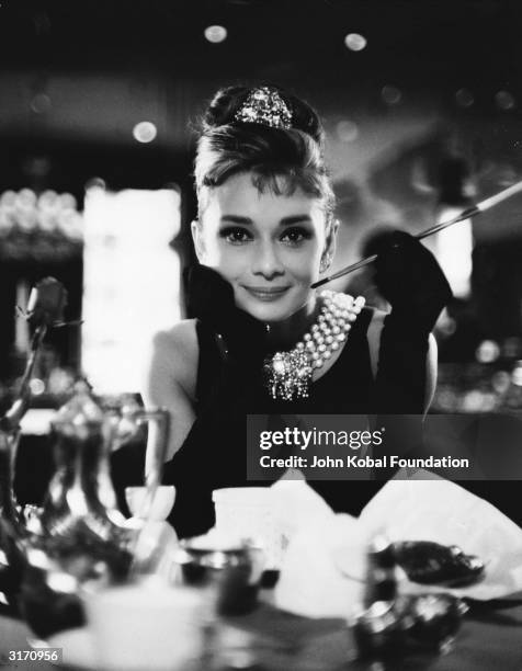 Audrey Hepburn wields a cigarette holder in her role as the charming gold-digger Holly Golightly in 'Breakfast at Tiffany's', directed by Blake...
