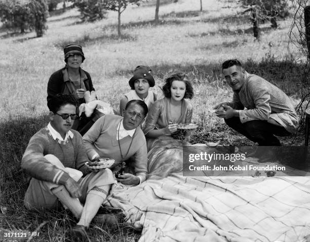 Swedish-American actress Greta Garbo off set with film director Edmund Goulding and her co-star John Gilbert during the filming of the romantic drama...