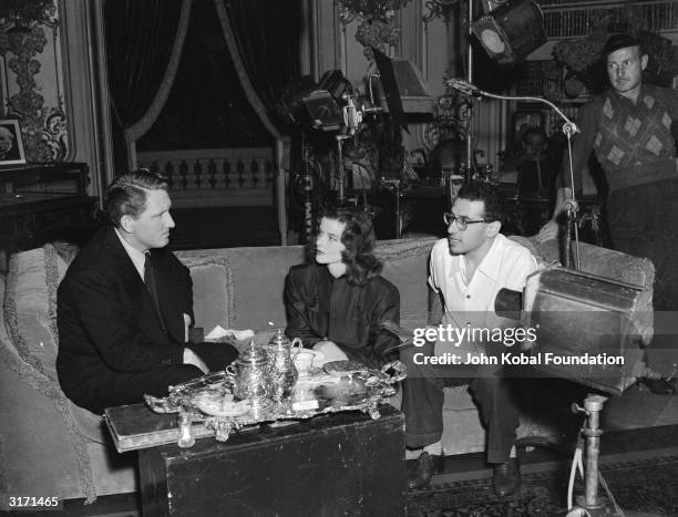 Director George Cukor discusses the film script with stars Katharine Hepburn and Spencer Tracy on the set of the MGM film 'Keeper of the Flame'....