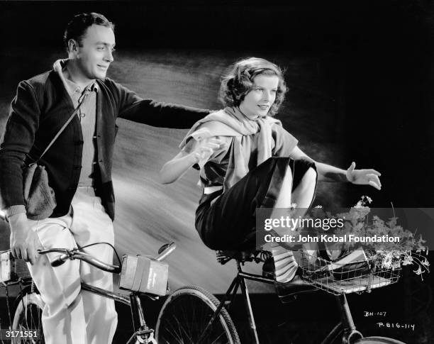 Katharine Hepburn shows off her cycling ability to Charles Boyer in a romantic scene from 'Break of Hearts', directed by Philip Moeller.