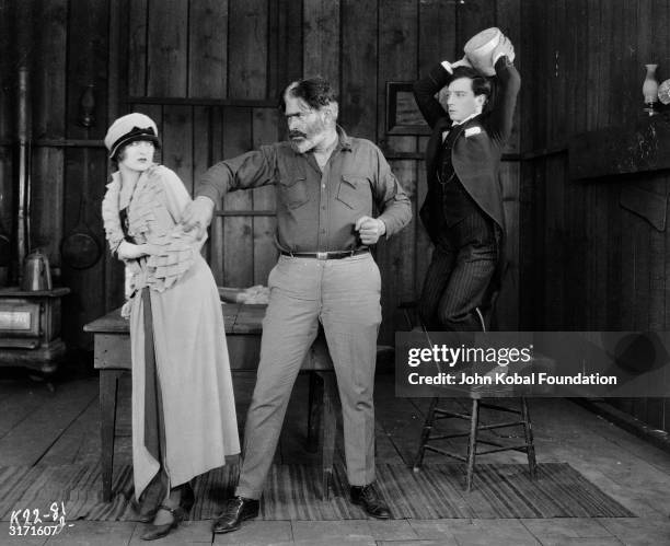 American comedian Buster Keaton about to hit villain Tom Murray on the head with a jar in order to save his true love, Kathryn McGuire, in a scene...