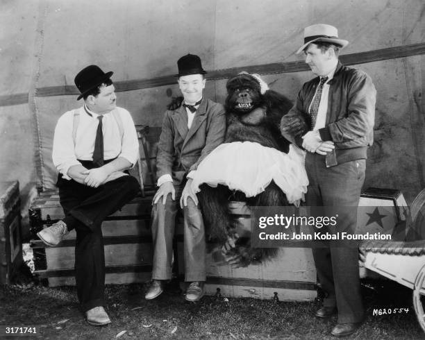 Stan Laurel and Oliver Hardy with producer Hal Roach during filming of 'The Chimp', directed by James Parrott. In the film Ethyl the chimp has been...