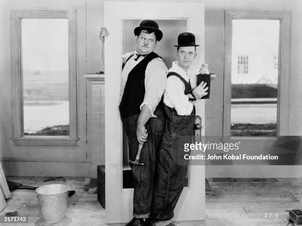 Stan Laurel and Oliver Hardy making things difficult for themselves in a scene from 'The Finishing Touch', directed by Leo McCarey and Clyde Bruckman.
