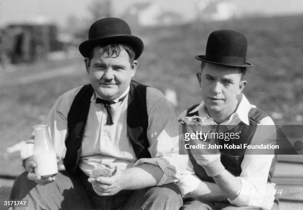 Stan Laurel and Oliver Hardy stop for milk and sandwiches, during a break from filming the silent short 'The Finishing Touch', directed by Leo...