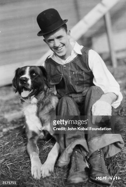 Stan Laurel with a dog, during a break from filming 'The Finishing Touch' directed by Leo McCarey and Clyde Bruckman.