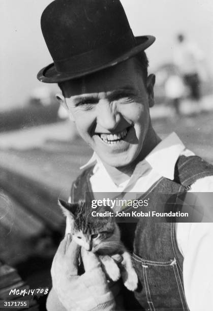 Stan Laurel holds a kitten during filming of 'The Finishing Touch' directed by Leo McCarey and Clyde Bruckman.