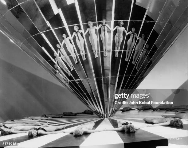 Chorus girls lie in a circle and join hands in order to form an unusual image in the mirrored cone above, in the musical extravaganza 'Dancing Lady',...