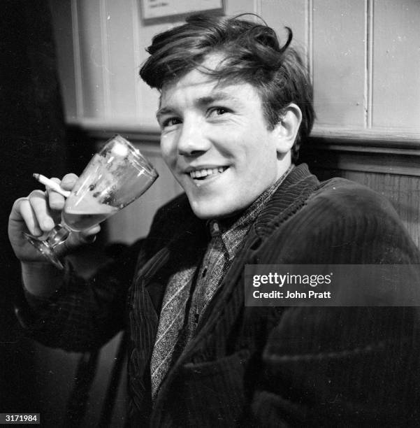 British film and stage actor Albert Finney enjoying a glass of beer in his regular pub behind the Cambridge Theatre in London, February 1961.