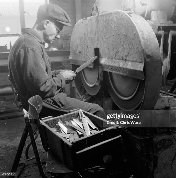 Worker cleaning new carving knife blades during the abrasive process that follows knife grinding at a Sheffield steel factory.