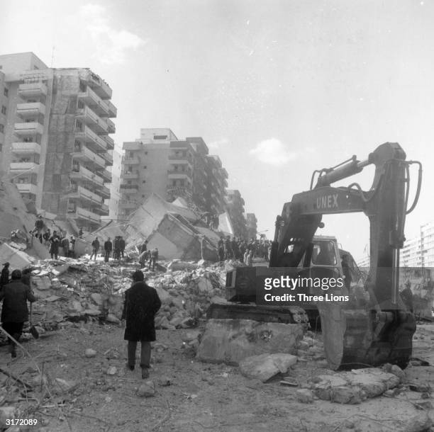 Rescue workers use a digger to sift through the remains of a block of flats after an earthquake in Bucharest which resulted in the loss of over 1,500...