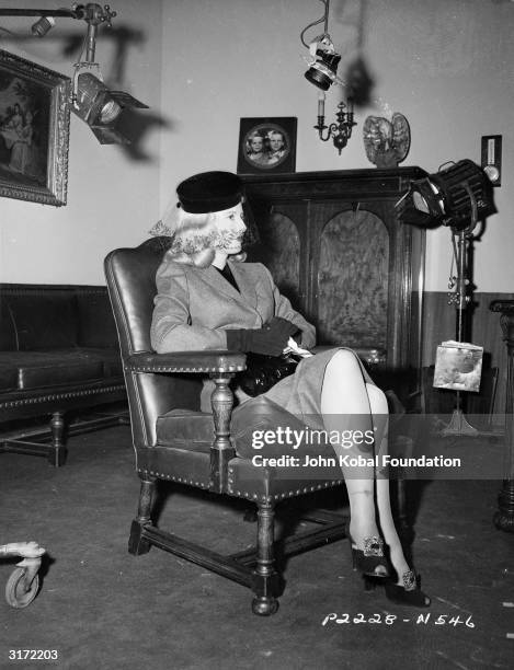 American actress Barbara Stanwyck in costume as the scheming Phyllis Dietrichson on the set of the film noir classic 'Double Indemnity', directed by...