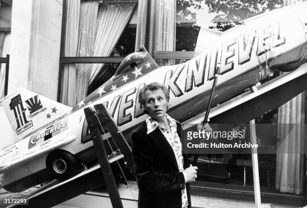 American stunt artist Evel Knievel points to his Sky-Cycle X-2 plane, which he used to jump across the Snake River Canyon in Idaho, as he talks to...