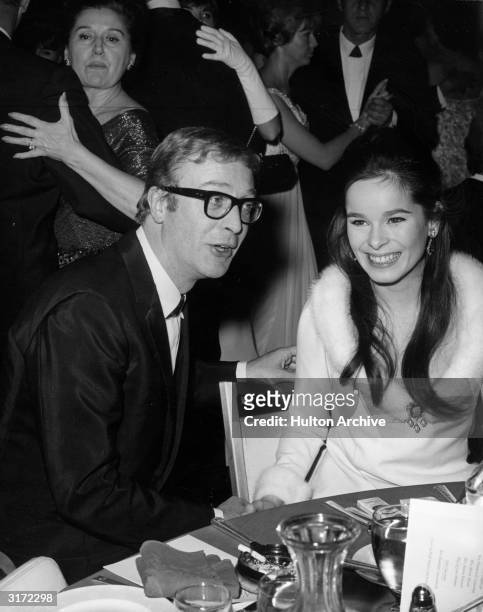 British actor Michael Caine talks with actor Geraldine Chaplin, Charlie Chaplin's daughter, at an after-theater party, while people dance in the...