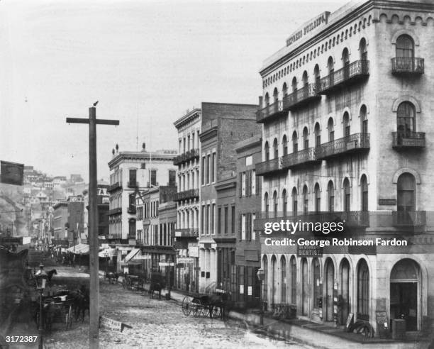 Horse-drawn carriages parked in front of buildings along the east side of Montgomery Street in San Francisco, California. A carriage that moved...
