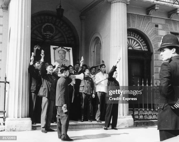 Group of Chinese men hold up their copies of the Little Red Book during a demonstration on the front steps of the Legation during the Chinese...