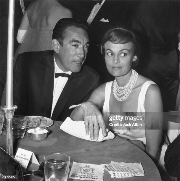 Mexican-born actor Anthony Quinn leans in to talk to his wife, American actor Katherine DeMille , at a dining table at the Helpers Charity party,...