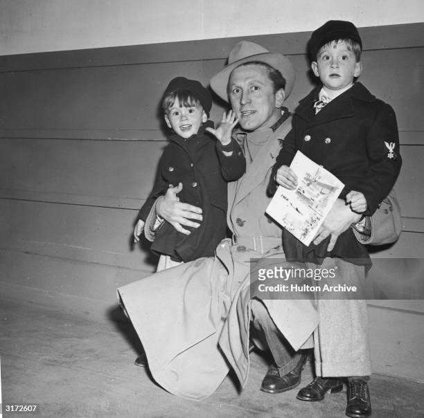 American actor Kirk Douglas kneels beside his sons, Joel and Michael . All three wear winter coats. Michael is carrying a comic book.