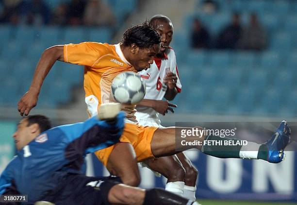 Ivory Coast's Didier Drogba vies with two Tunisian players Ali Boumnigel and Hatem Trabelsi , to score the first goal for Ivory Coast during their...