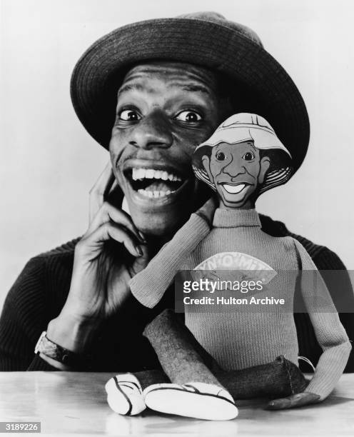 Promotional portrait of American actor Jimmie Walker as he poses with a talking doll based on his character 'J. J.' from the television series 'Good...