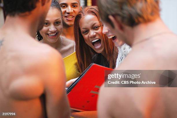 Two unidentified, shirtless male models frame the cast of the UPN television series 'America's Next Top Model,' Milan, Italy, October 16, 2003. Left...