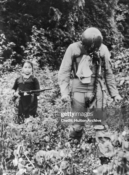 North Vietnamese woman or girl points a rifle at American POW Gerald Santo Venanzi, a first lieutenant in the U.S. Air Force, as he walks in front of...