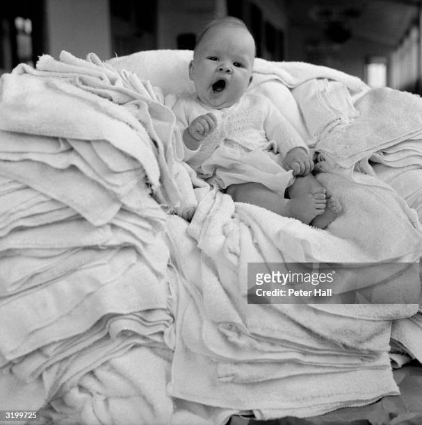 Baby rests on a pile of nappies in the laundry room at Butlin's Holiday Camp at Clacton-on-Sea, Essex.
