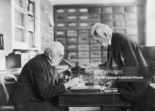Brothers Auguste and Louis Lumiere , French scientists, inventors, and photographers, use a microscope in their laboratory. Auguste looks through the...