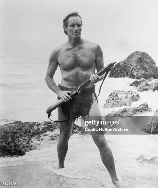 American actor Charlton Heston holds a rifle as he stands in the surf in a still from director Franklin Schaffner's film, 'Planet of the Apes.' He is...