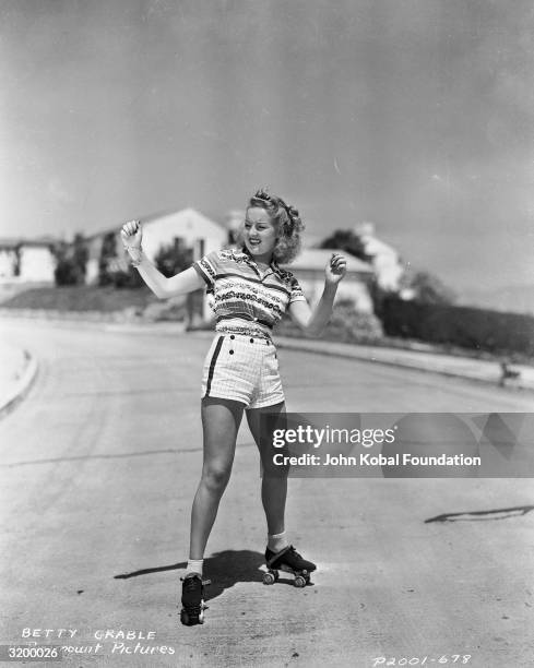 American actress Betty Grable balancing on a pair of roller skates.