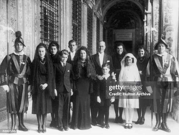 Ambassador to England Joseph P. Kennedy , his wife Rose , and eight of their children standing between two guards outside the Papal residence at...