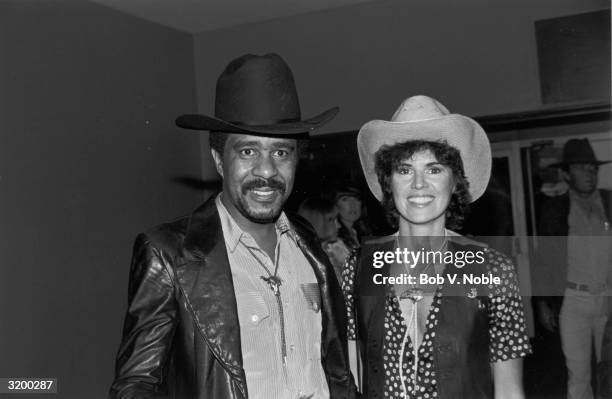 American comedian and actor Richard Pryor and his future wife, Jennifer Lee, wearing cowboy hats and bolo ties, smile while at the annual SHARE...