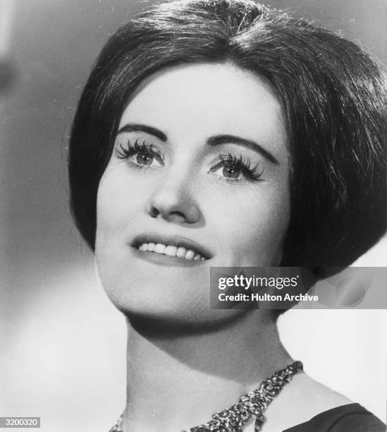 Closeup portrait of Australian opera singer Joan Sutherland smiling. She is wearing a jeweled necklace.