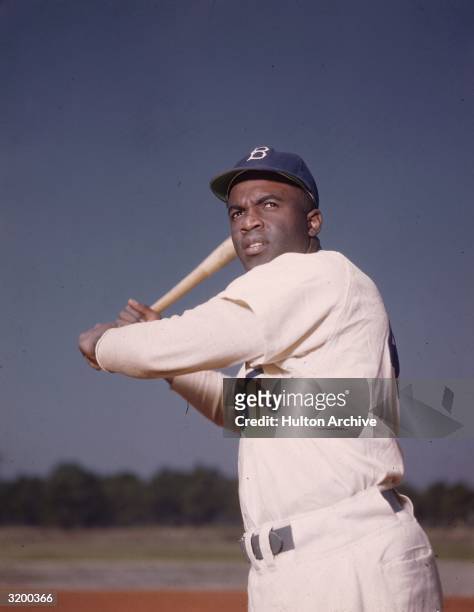 Portrait of the Brooklyn Dodgers' Jackie Robinson in uniform, preparing to swing a baseball bat.