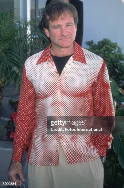 American actor and comedian Robin Williams, wearing a Jean Paul Gaultier shirt with a print of a muscular chest and abdomen, at an unspecified event,...