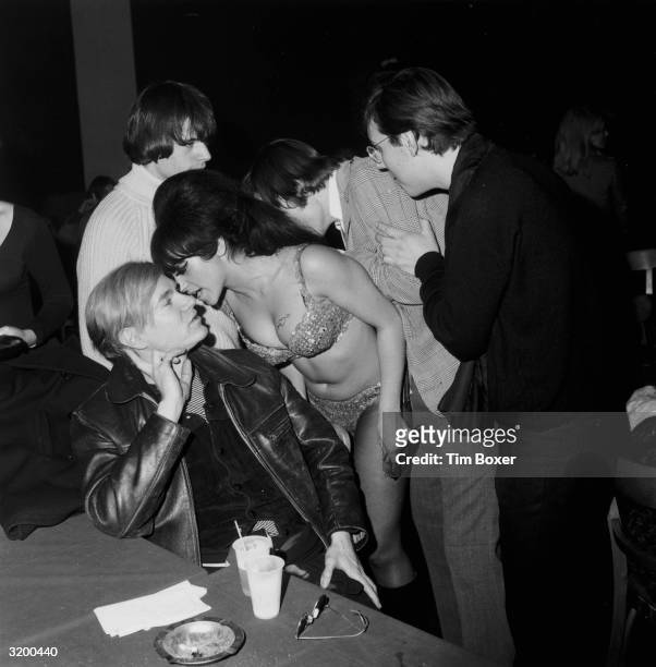 Female go-go dancer whispers into the ear of American Pop Artist Andy Warhol during a Velvet Underground and Nico performance in a 'Freakout' party...